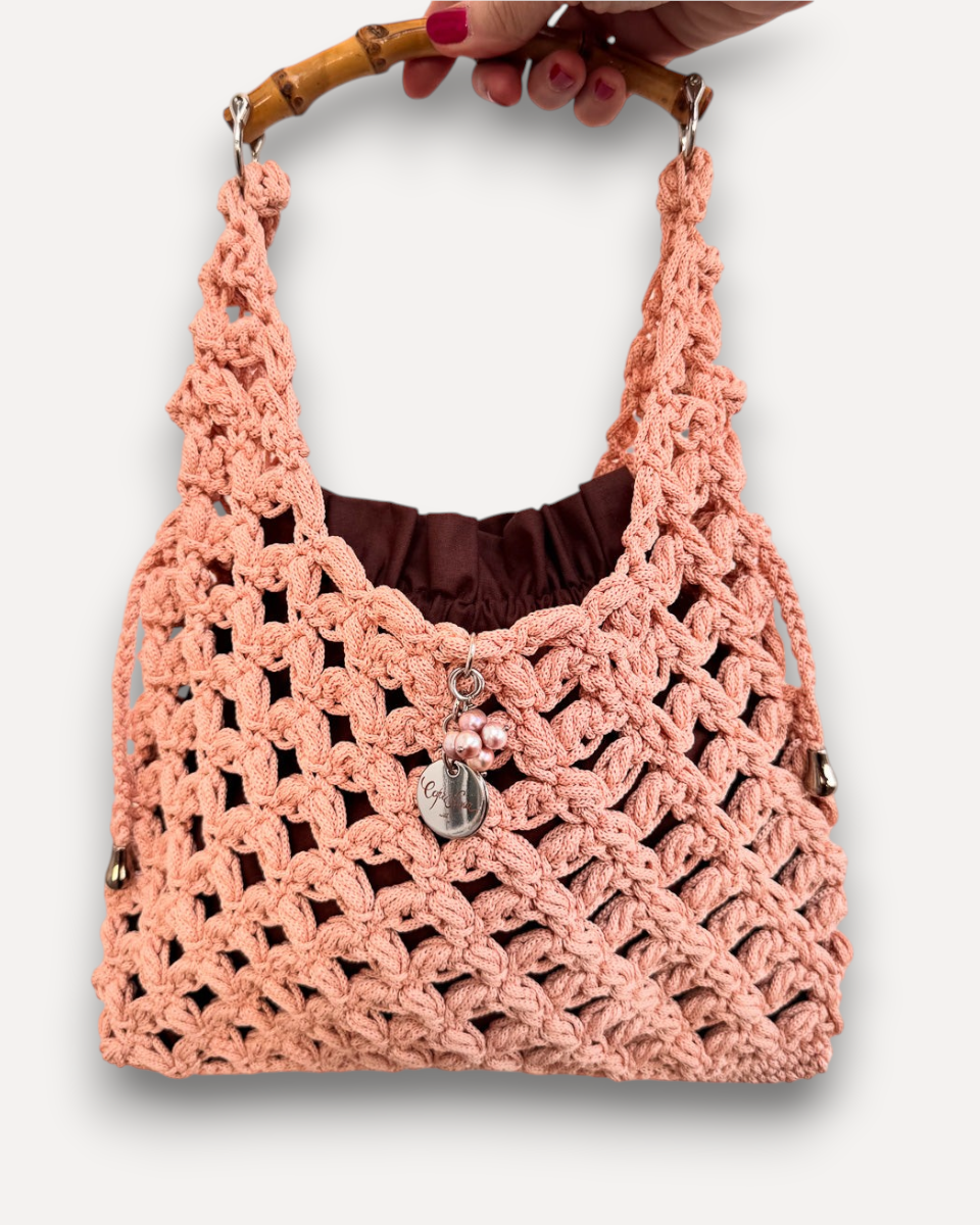 Borsa all'uncinetto CapriNina color pesca con manico in bambù e sacca interna marrone, design artigianale elegante.