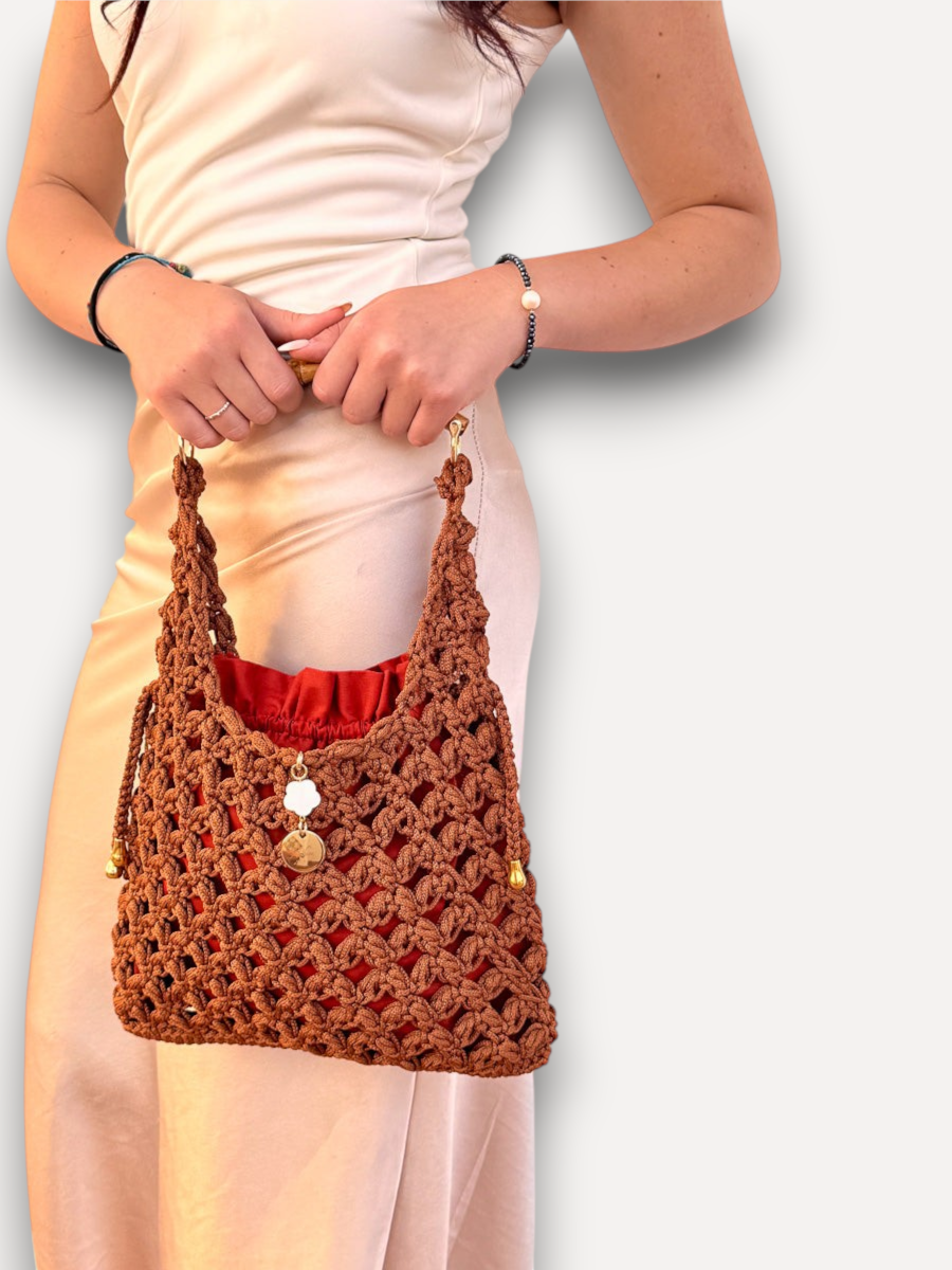 Borsa a mano CapriNina in crochet marrone con manico in bambù e pochette interna rossa, indossata con abito satin