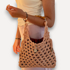 Borsa all'uncinetto CapriNina color pesca con manico in bambù e sacca interna, indossata a braccio