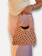 Borsa a mano CapriNina in crochet color pesca con manico in bambù e pochette interna, indossata con gonna satinata