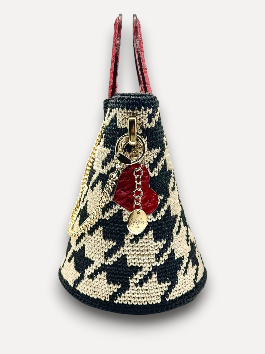 Borsa CapriNina Dodie in crochet con motivo pied de poule nero e beige, manici in pelle rossa e ciondolo a cuore.